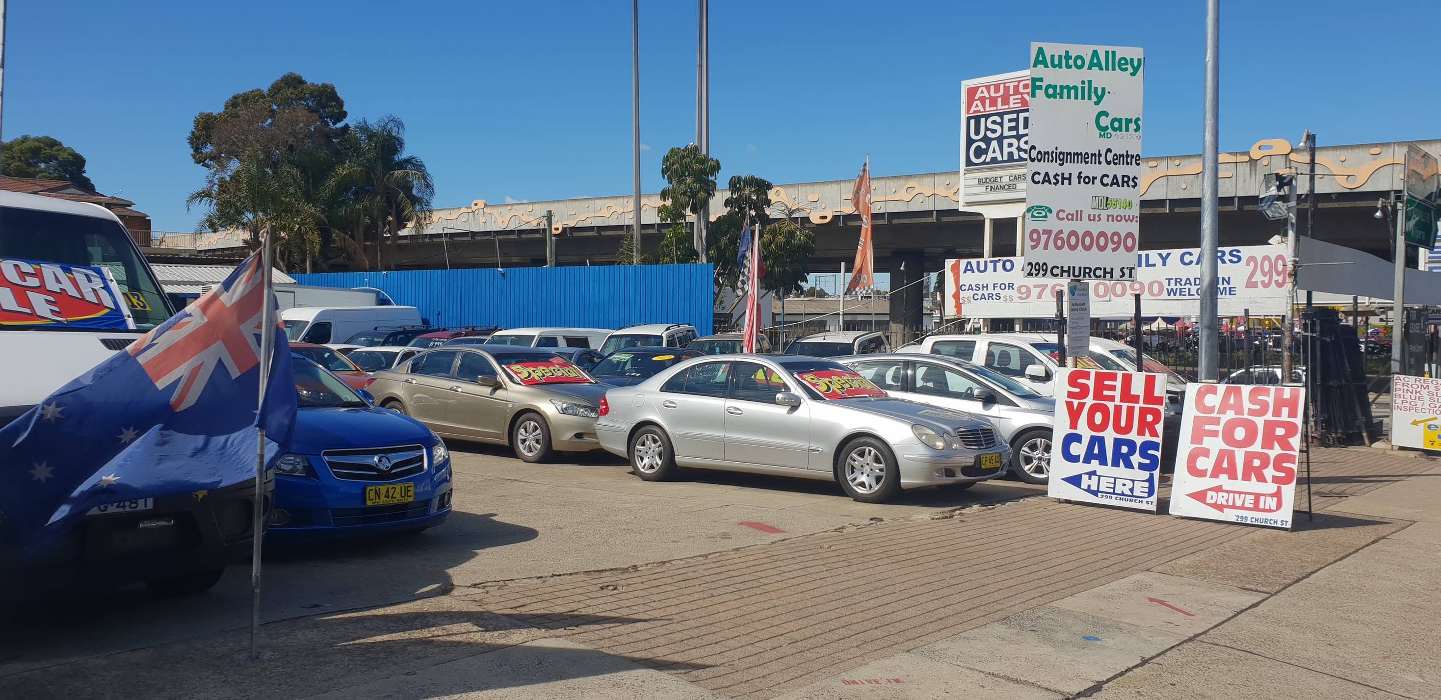 Sell Your Cars Here and Cash For Cars Drive In boards at the kerb on Church Street, with the pylon sign behind